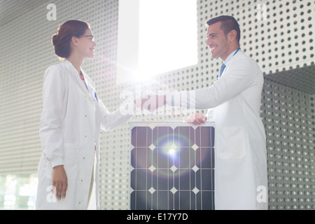 Scientists handshaking at solar panel in laboratory Stock Photo