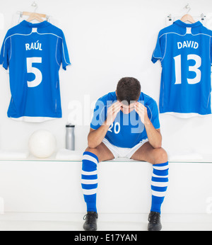 Soccer player with head in hands in locker room Stock Photo