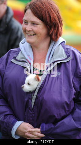 Woman keeps her dog dry under her coat at Hove Carnival today as rain and poor weather hit the bank holiday Stock Photo