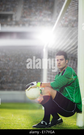 Goalie holding soccer ball by net Stock Photo