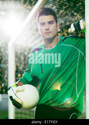 Goalie holding soccer ball in net Stock Photo