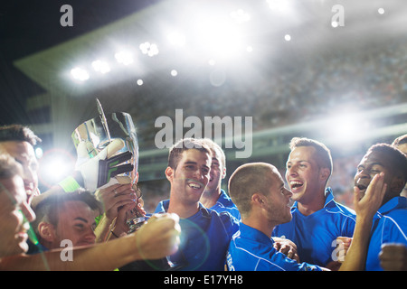 Soccer team celebrating with trophy on field Stock Photo