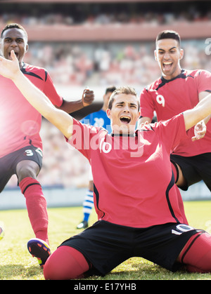 Soccer team celebrating on field Stock Photo