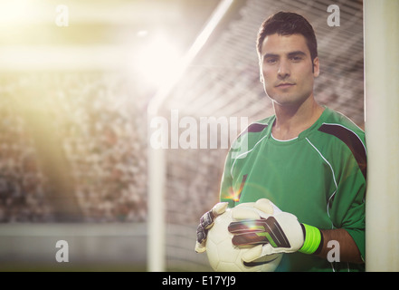 Goalie holding ball in soccer net Stock Photo