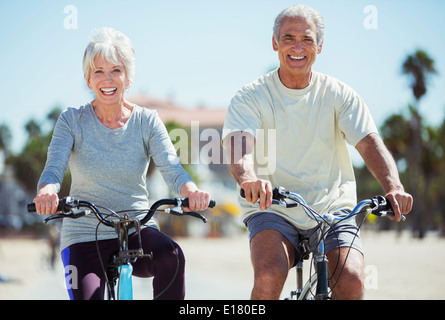 Portrait of senior couple riding bicycles on beach Stock Photo
