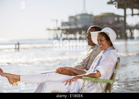 Couple relaxing in lawn chairs on beach Stock Photo