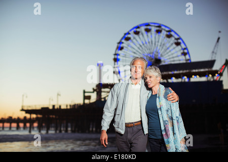 Senior couple walking on beach at night Stock Photo