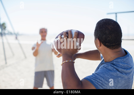 Senior men playing football on beach Stock Photo