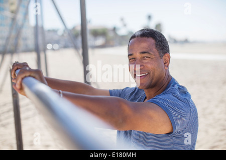 Portrait of senior man leaning on bar at beach playground Stock Photo