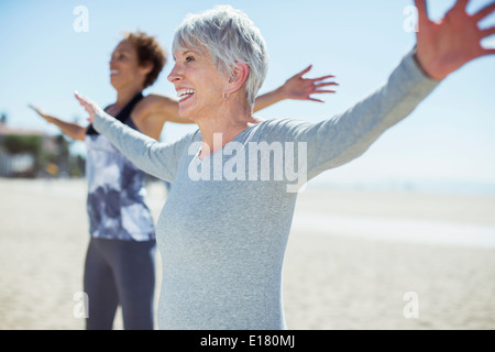 Senior women stretching arms on beach Stock Photo
