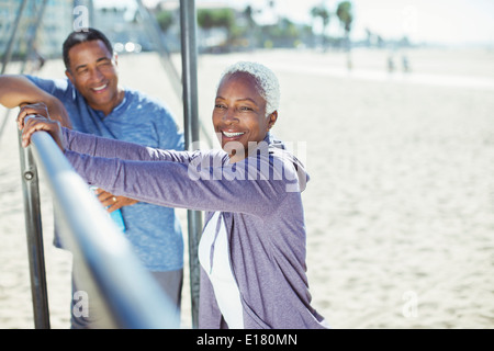 Portrait of senior couple leaning on bar at beach playground Stock Photo