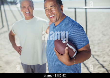 Portrait of senior men with football on beach Stock Photo