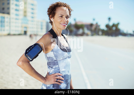 Confident jogger resting on beach boardwalk Stock Photo