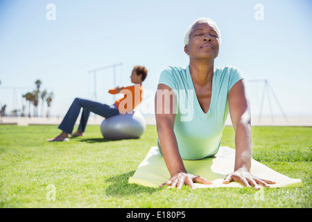 Women practicing yoga in sunny park Stock Photo