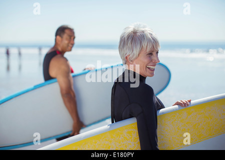 Senior couple carrying surfboards on beach Stock Photo