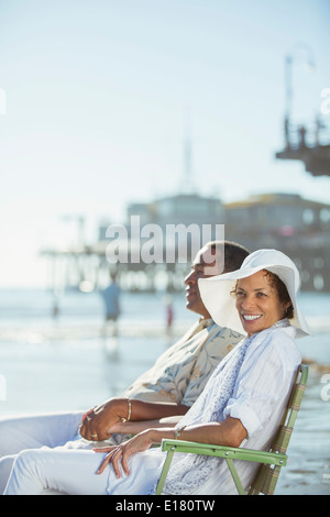 Portrait of couple relaxing in lawn chairs on sunny beach Stock Photo