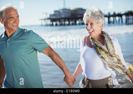 Enthusiastic senior couple running on beach Stock Photo