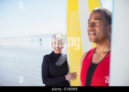 Portrait of senior couple with surfboards on beach Stock Photo