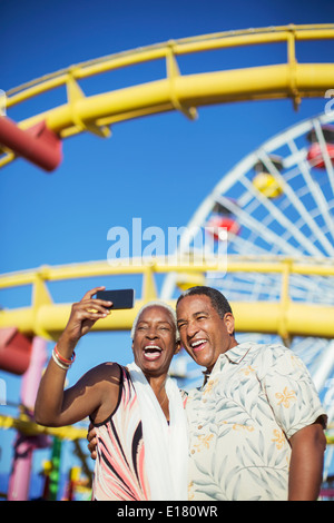 Senior couple taking selfie at amusement park Stock Photo