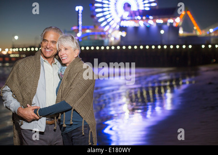 Senior couple hugging on beach at night Stock Photo