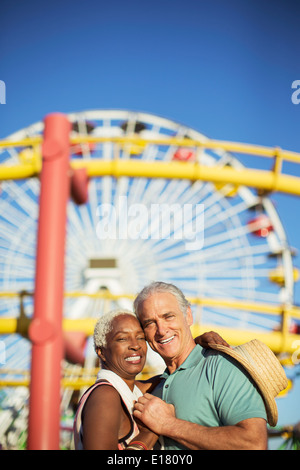 Portrait of happy senior couple hugging at amusement park Stock Photo