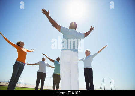 Seniors practicing yoga under sunny blue sky Stock Photo