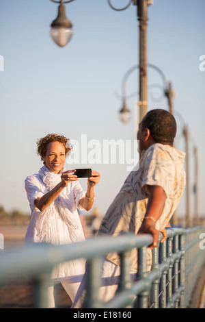 Woman photographing man on pier Stock Photo