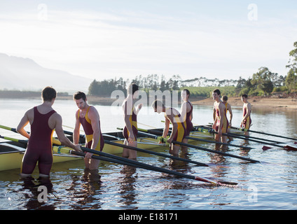 Rowing team placing boat on lake Stock Photo