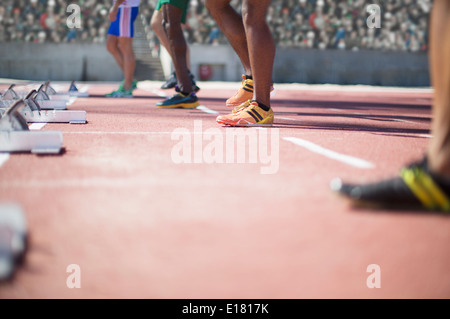 Runners standing at starting blocks on track Stock Photo