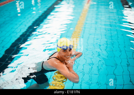 Portrait of smiling swimmer leaning on swimming lane marker in pool Stock Photo