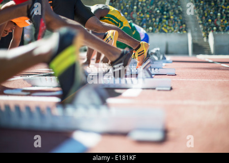 Runners poised at starting blocks on track Stock Photo