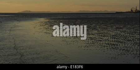 Orange sunset view, towards Blackpool and the Cumbrian Mountains, from the low tide shoreline at St Annes Beach, Fylde Coast, UK Stock Photo