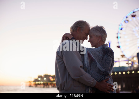 Senior couple hugging on beach at sunset Stock Photo