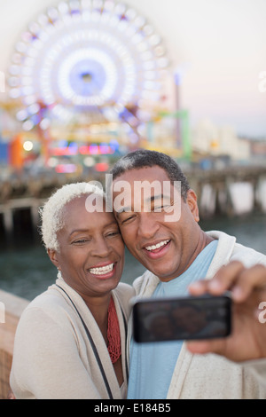 Senior couple taking selfie at amusement park Stock Photo