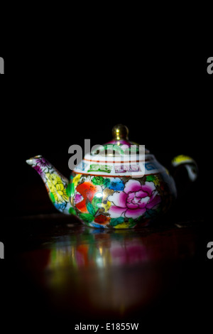 A teapot sit on laid lying superficially attractive and smooth intensely deep bright vivid of pattern flowers blooms blossom Stock Photo