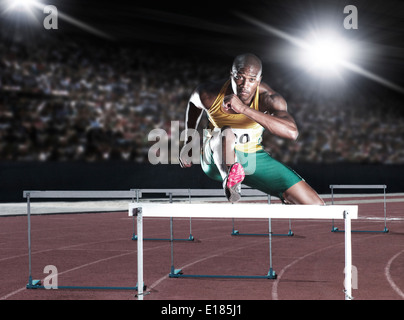 Runner clearing hurdle on track Stock Photo