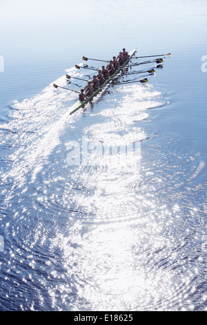 Rowing team rowing scull on sunny lake Stock Photo