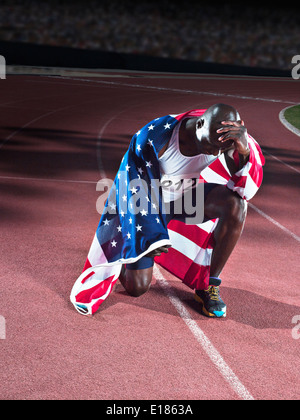 Track and field athlete wrapped in American flag on track Stock Photo