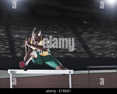 Runner jumping hurdle on track Stock Photo