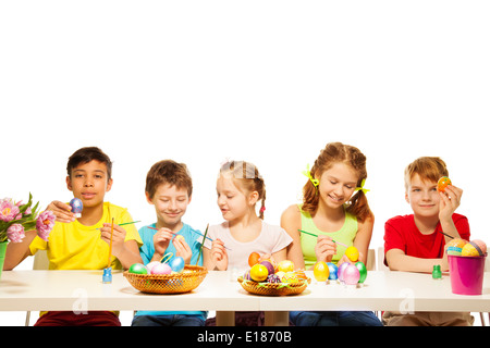 Five kids with colourful Eastern eggs at table Stock Photo