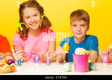 Boy and girl painting Easter eggs at the table Stock Photo