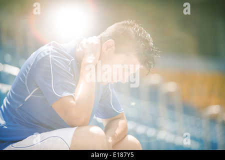 Disappointed soccer player sitting in stadium Stock Photo