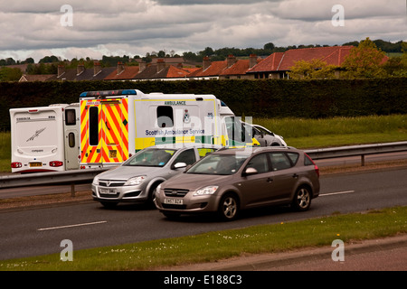 Scottish NHS Ambulance Service passing cars along the Dual Carriageway responding to a 999 emergency call in urban Dundee, UK Stock Photo