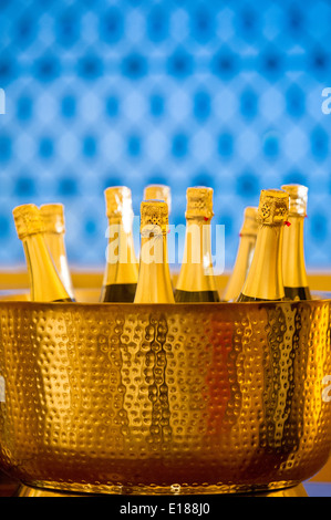 Champagne bottles in a gold colored bucket against a blue background, in Baltimore, Maryland, USA Stock Photo