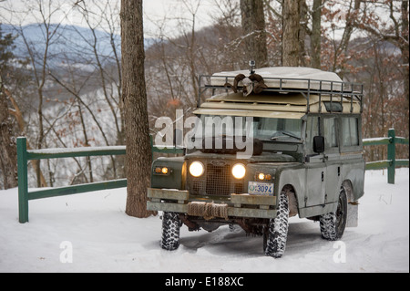 Vintage Land Rover parked near green fence with headlights on, in Green Ridge State Forest in Western Maryland, USA Stock Photo