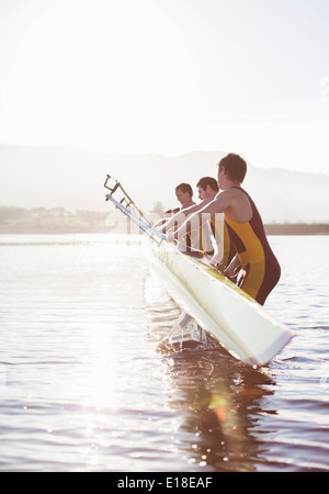 Rowing team placing boat in lake Stock Photo