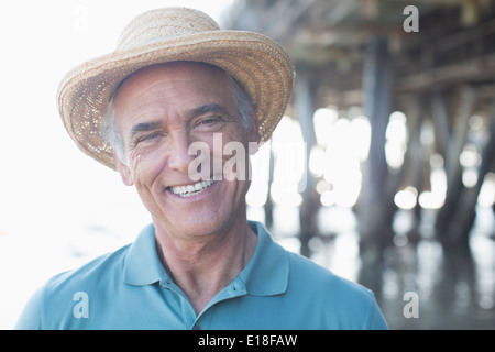 Portrait of smiling senior man in sun hat at beach Stock Photo