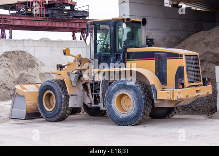 Front end loader with its bucket or scoop down parked in front of a warehouse on paving Stock Photo