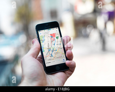 Person hand with iPhone displaying Google maps GPS navigator on streets of Tokyo, Japan. Stock Photo