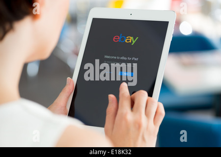 Woman holding a white Apple iPad Air with eBay welcome message on a screen Stock Photo
